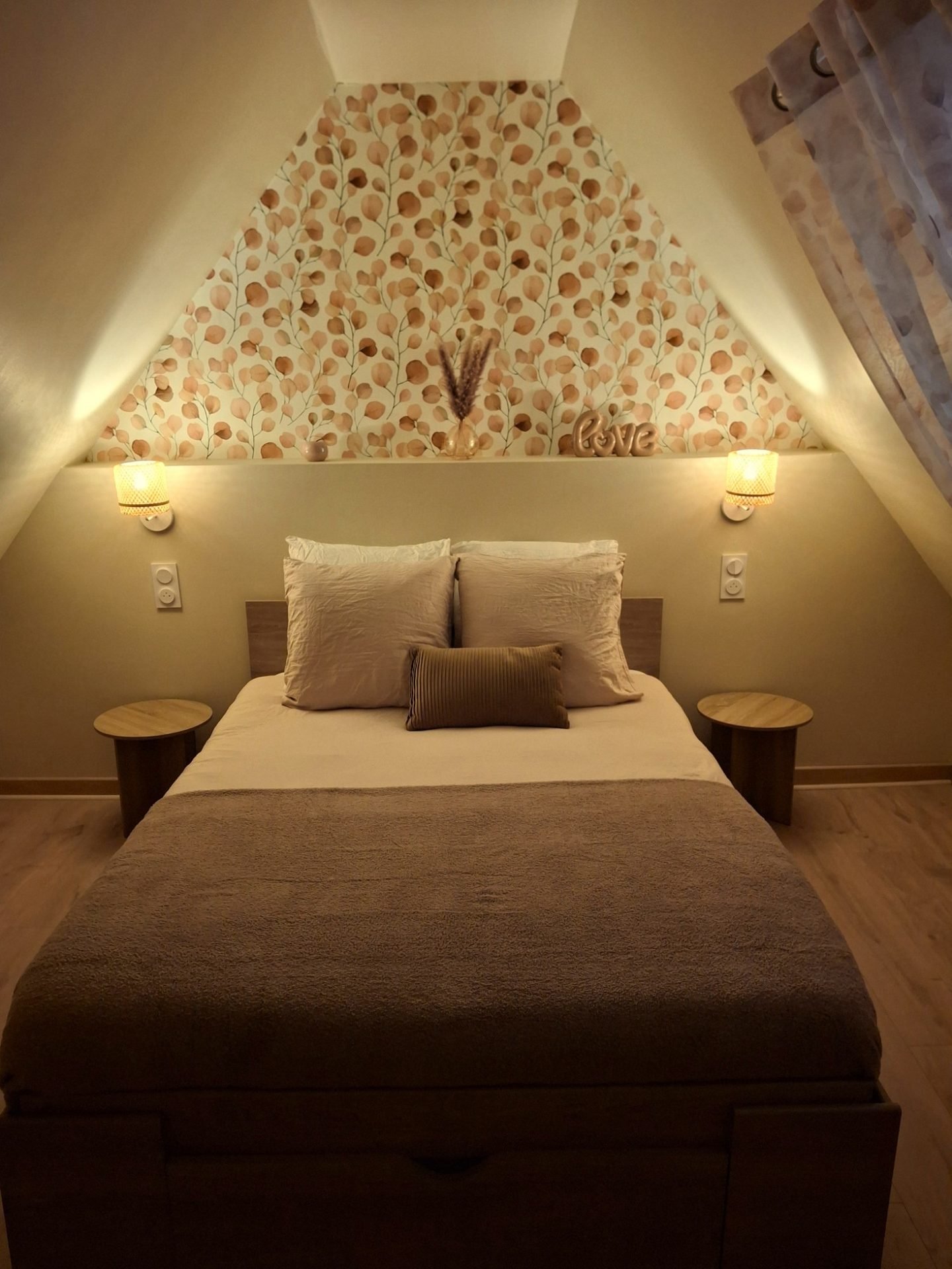 Chambre eucalyptus, papier peint de feuilles rose poudré et lumière douce des appliques