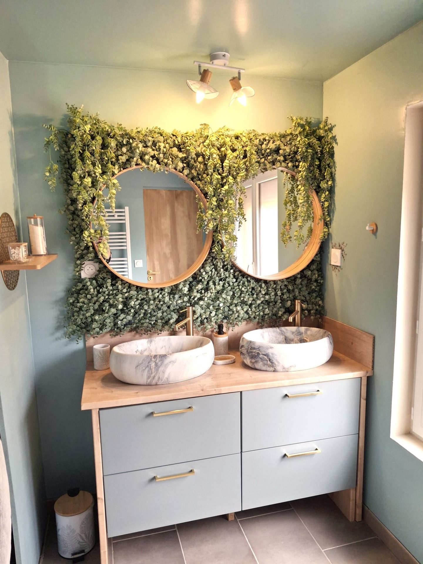Salle d'eau : double vasque en marbre, miroirs ronds en bois et mur végétal d'eucalyptus